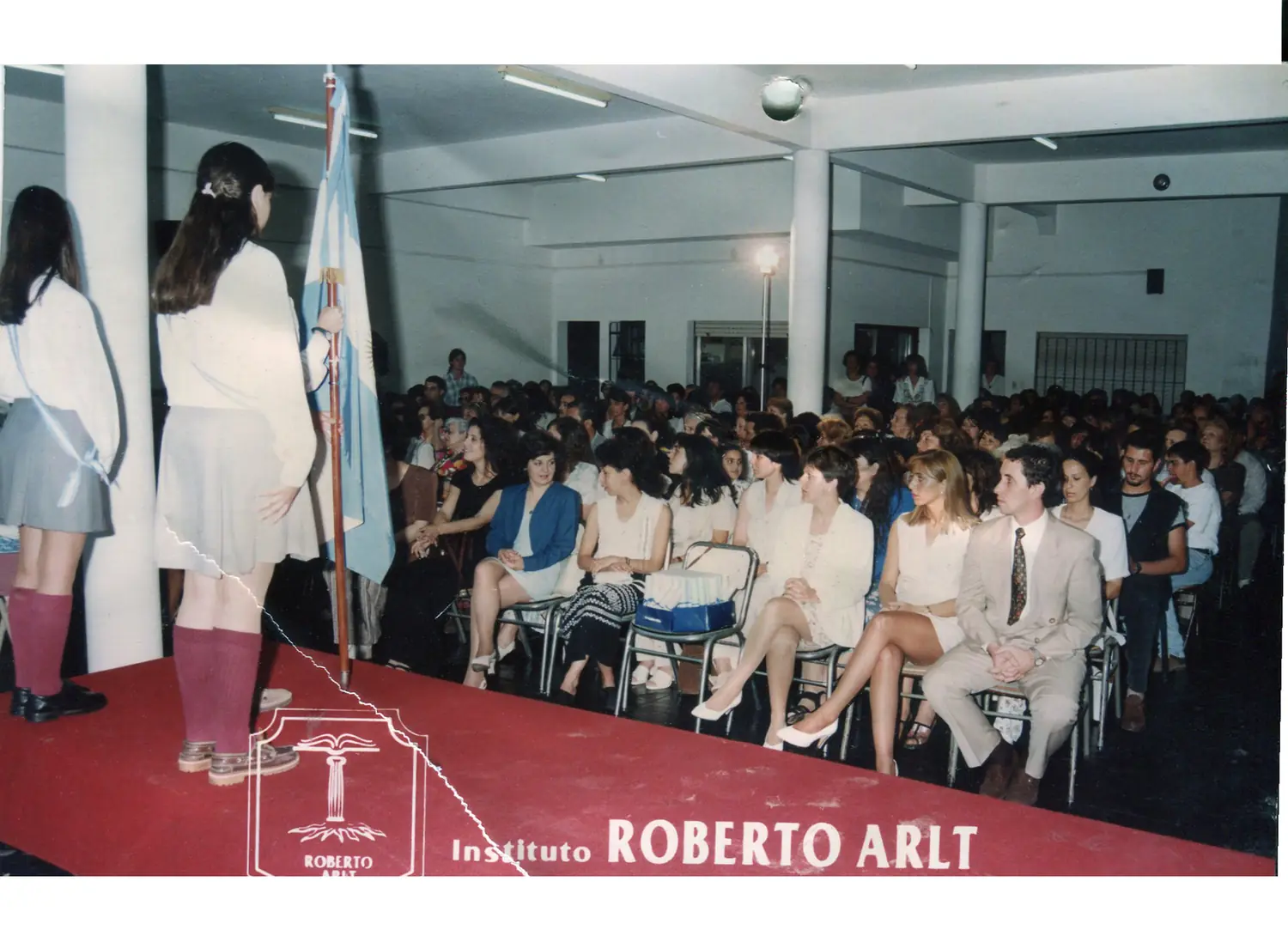 Abanderadas en un acto, con el salón lleno