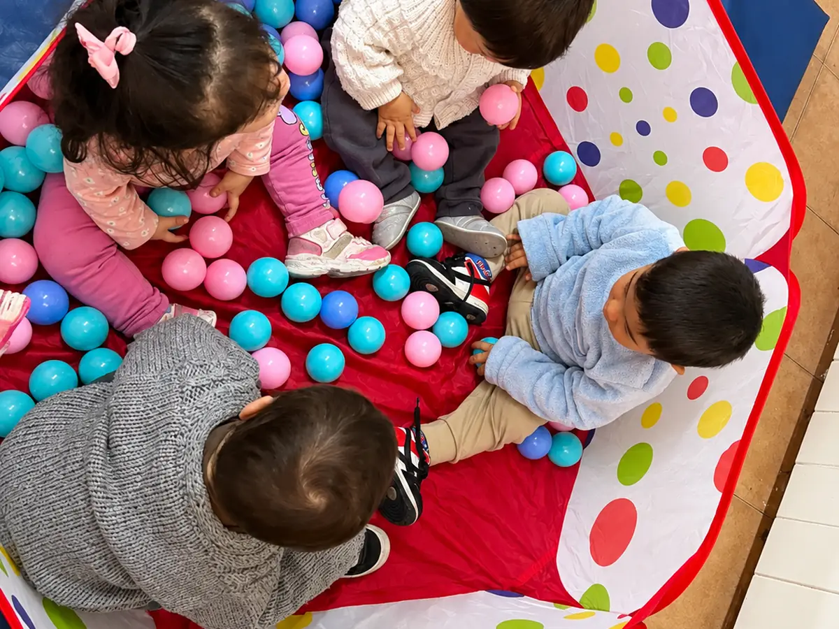 Bebés jugando con pelotas en la sala de maternal